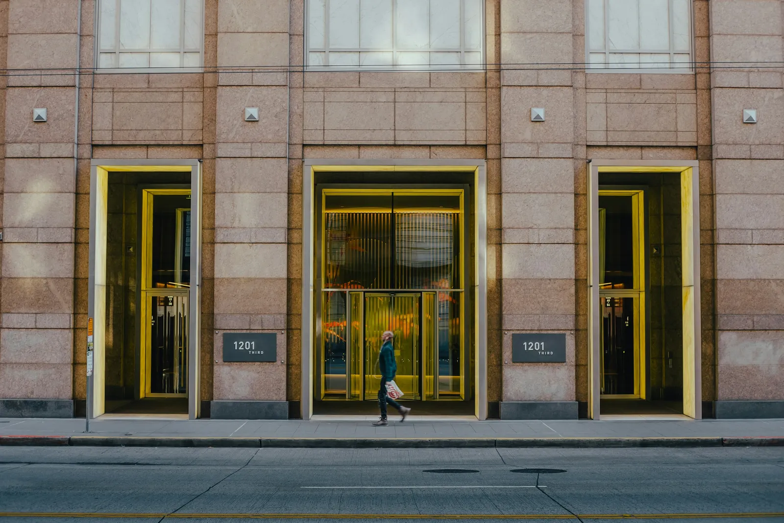 Person walking past a sunlit building at golden hour